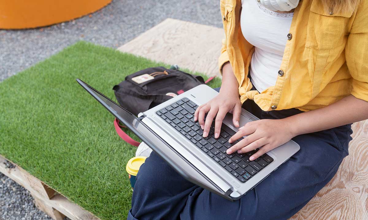Person sitter med en dator i knät och skriver