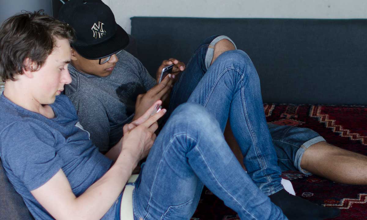 Två killar tittar i sina telefoner